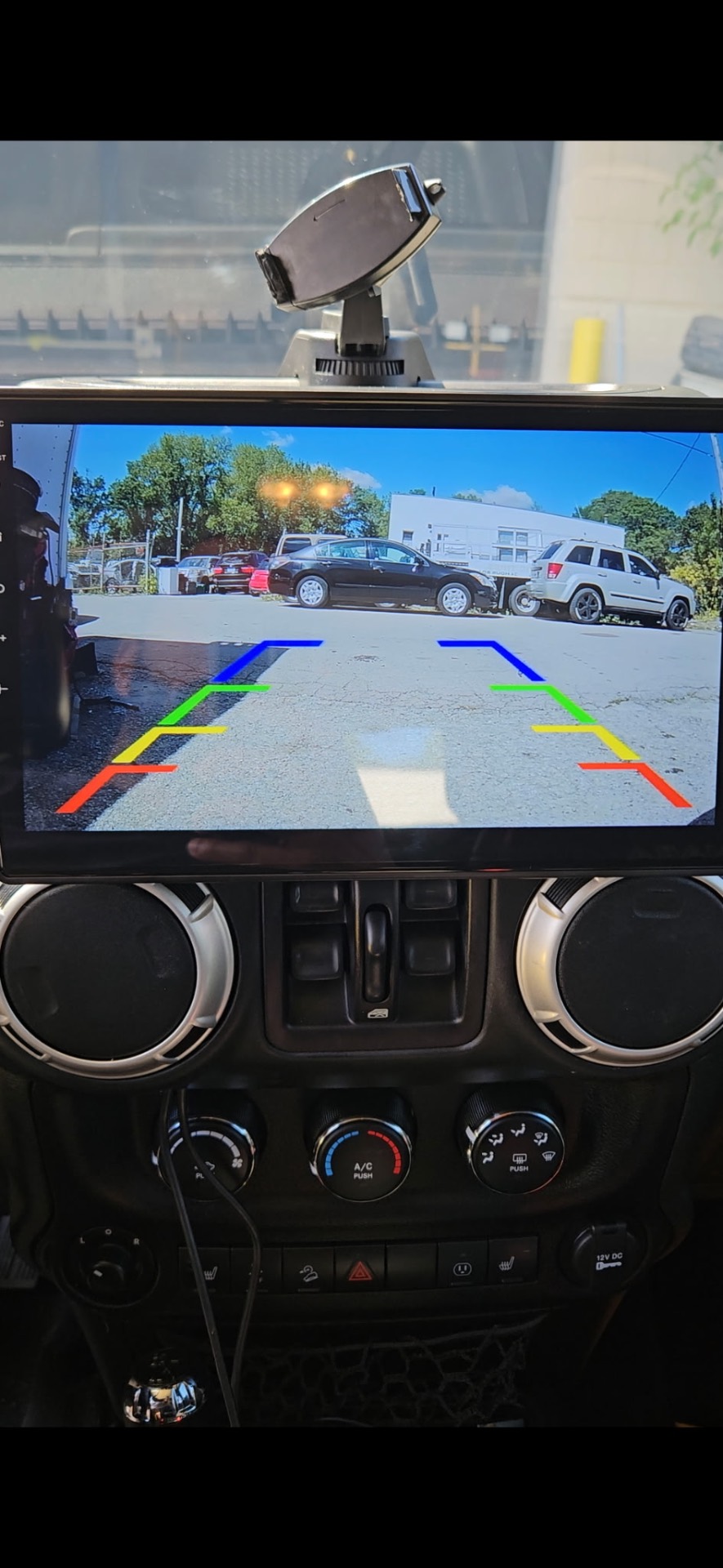 HD backup camera display showing rearview with colored guidelines mounted in a Jeep dashboard