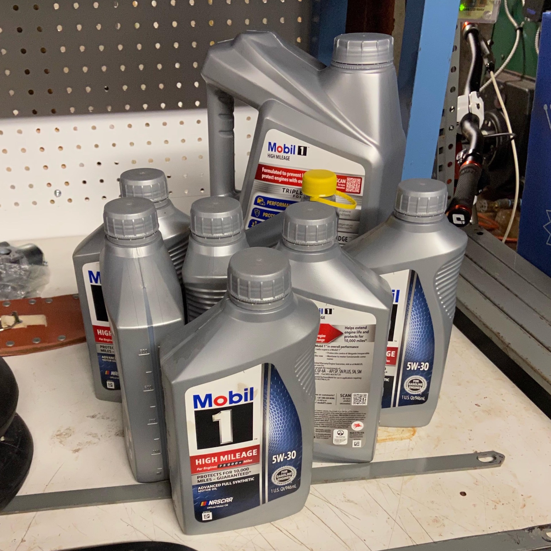 Mobil 1 High Mileage 5W-30 full synthetic motor oil bottles on a shop bench